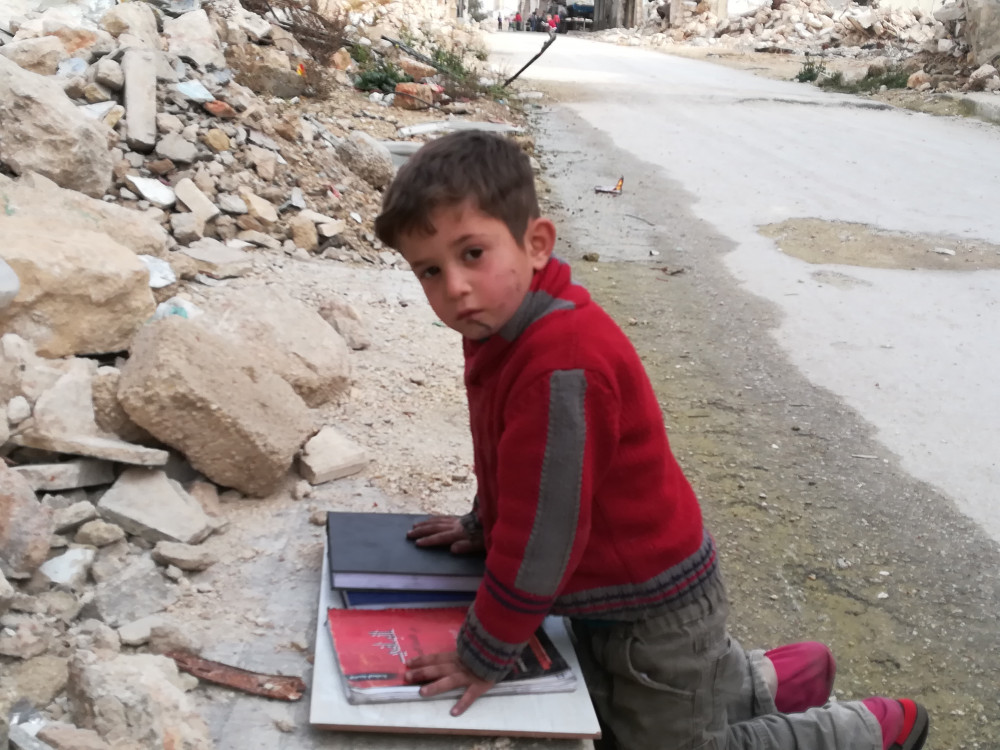 chlopiec w Aleppo uczacy sie ze znalezionych ksiazek na ulicy